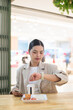 © Ranta Images - Young Thai Isan businesswoman checking the time on her smartwatch during lunch break