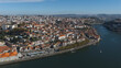 © Amazing Aerial - Aerial view of the historic city of Porto along the Douro River, featuring dense terracotta rooftops, traditional architecture, and the Dom Luis I Bridge, Porto, Porto District, Portugal.