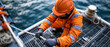 © Mrammon - Offshore worker safety gear orange uniform hard hat rope gloves sea industrial maritime deck worker concentrating while handling rope on offshore vessel near ocean water