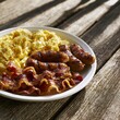 © Khawla - Hearty Breakfast Plate with Sausages Scrambled Eggs and Bacon in Warm Morning Sunlight