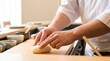 © Stitch - Japanese sushi chef molding a portion of white rice with his hands on a wooden cutting board