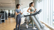 © Hiiro-Studio - Smiling Japanese woman running on a treadmill with trainer holding a clipboard