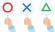 © Roni Ahmod - Hands holding voting paddles with red circle, blue cross and green triangle symbols