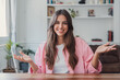 © Daniel - Smiling woman making an open gesture with her hands while engaging in a video call from her home office, communicating effectively and showing positivity and friendliness
