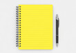 © Sahara - Bright yellow spiral notebook with black pen on gray textured background