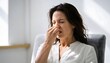 © Ірина Пальцева - Woman Pinch Nose Close Eyes Odor Frown Disgust Unpleasant Smell Sitting Indoors Home Office Environment Bad Aroma Facial Expression Adult Female Stress Unhappy Feel