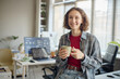 © TrueFrame Collective - Portrait of young adult Caucasian woman holding coffee mug and smiling in office, representing workplace confidence and creative routine. Ideal for remote work or startup marketing
