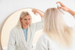 © Pixel-Shot - Young blonde man with hair spray near mirror in bathroom