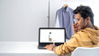 © Caca - Young man using laptop to edit online e-commerce product imagery for fashion retail business