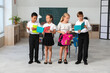 © Pixel-Shot - Little classmates with notebooks and backpacks in classroom
