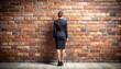 © EPDICAY - Businesswoman standing before a brick wall, symbolizing obstacles, career challenges, problem solving, perseverance, limitations, and strategic thinking.