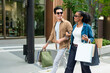 © Kawee - Latino man and Black woman walking outdoors while shopping in the city.