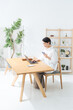 © metamorworks - 部屋でスマホとノートパソコンを使う女性。アプリ、フリーランス、仕事、ライフスタイル、DX