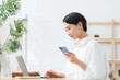 © metamorworks - スマホとノートパソコンを使う女性。アプリ、ネットショッピング、認証、DX