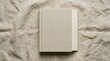 © AlHarits - Closed linen book on wrinkled fabric background