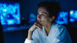 © CinimaticWorks - closeup of a thoughtful woman with curly hair looking away pensively in a technology filled office with glowing screens in the background today scene photography