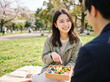 © Anoconone - 春の公園ピクニックでお弁当を広げて微笑む女性
