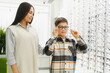 © Serhii - Mother and son choosing new eyeglasses in optical shop