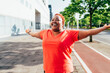 © Westend61 - Smiling woman standing with arms outstretched on footpath