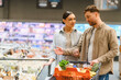 © Serhii - Couple shopping for groceries selecting food items
