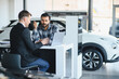 © Serhii - Car dealership salesman consulting customer about automobile purchase