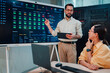© Zamrznuti tonovi - It professional explaining server rack alert status on a dashboard to a female colleague in a data center