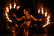© TiA - Female fire performer dancing with flaming fans at night