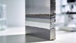 © Tina - Close-up of a cross-section of a composite material showing layers of metal and adhesive. The surface is smooth and shiny, highlighting the material's structure.