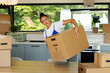 © Home-stock - Young woman struggling to lift large cardboard box during house move