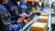 © Laura - Faceless portrait of female and male technicians using a tablet computer to monitor an automated conveyor belt with packages in a logistics warehouse, modern fulfillment center