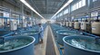 © Miftakhul - Industrial aquaculture facility with rows of large tanks and workers tending to fish.