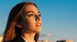 © Maryna - Young businesswoman gazes upward bathed in warm golden hour light. Stands on rooftop overlooking city skyline. Confident expression suggests ambition, future success. Pro attire conveys authority