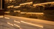 © Platon - A dark decorative stone brick wall inside a modern building with warm yellow hidden LED light strips reflecting on a shiny marble floor