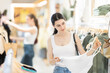 © JackF - Woman is choosing clothes with interest before vacation, she stands in the department with a new summer collection and chooses tops, pants and dresses. European woman shopping in summer