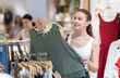 © JackF - Woman is looking at a women's clothing collection in a store, she stopped at the hangers with blouses and chooses her size