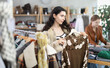 © JackF - Young woman buyer choosing warm knitted cardigan in clothing store