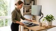 © Thumbs - Woman standing at a standing desk working on a laptop and computer