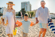 © Mimi - Grandparents Running Along Beach With Grandchildren On Summer Vacation