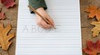© SimpleDesignStudio - Young Child Learning to Write Alphabet Letters on Lined Paper During Autumn Season Education Concept