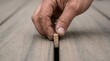 © SimpleDesignStudio - Close up of a carpenter hand installing wooden deck board spacer for precise gap spacing during outdoor patio construction