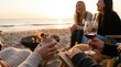 © Nina - Group of young adult female friends enjoying wine and conversation around a beach bonfire at sunset, cozy evening lifestyle concept
