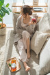 © buritora - A stylish Asian woman relaxing on a living room sofa during teatime.