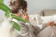 © buritora - A stylish woman sitting on a sofa and talking on her smartphone.