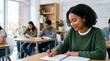 © Eve - Smiling young African American college student girl writing notes in notebook studying at desk in bright classroom