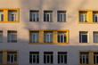 © Alina - Symmetrical facade of a modern residential building featuring yellow framed windows in sunset light to provide a minimalist architectural background with clean lines and urban patterns