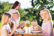 © deagreez - Family enjoying a sunny outdoor picnic together — multi-generation conversation and laughter at a garden table with grandparents, parents and children sharing food and drinks