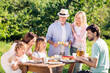 © deagreez - Multi-generation family enjoying an outdoor picnic together in a sunny garden with grandparents serving pastries and everyone smiling and sharing food