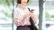 © Trickster* - オフィス街でスマートフォンを使う女性・ビジネスウーマン, Businesswoman Using a Smartphone in an Office District