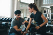 © chokniti - Trainer woman man gym dumbbell workout fitness exercise coaching strength focused personal training session with dumbbell lift, athletic couple practicing weight exercise modern indoor health club