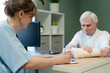 © Sk Elena - Doctor and senior patient in collaborative health discussion. Elderly man engaging with attending professional during consultation. Shared understanding and communication for older patient in clinic